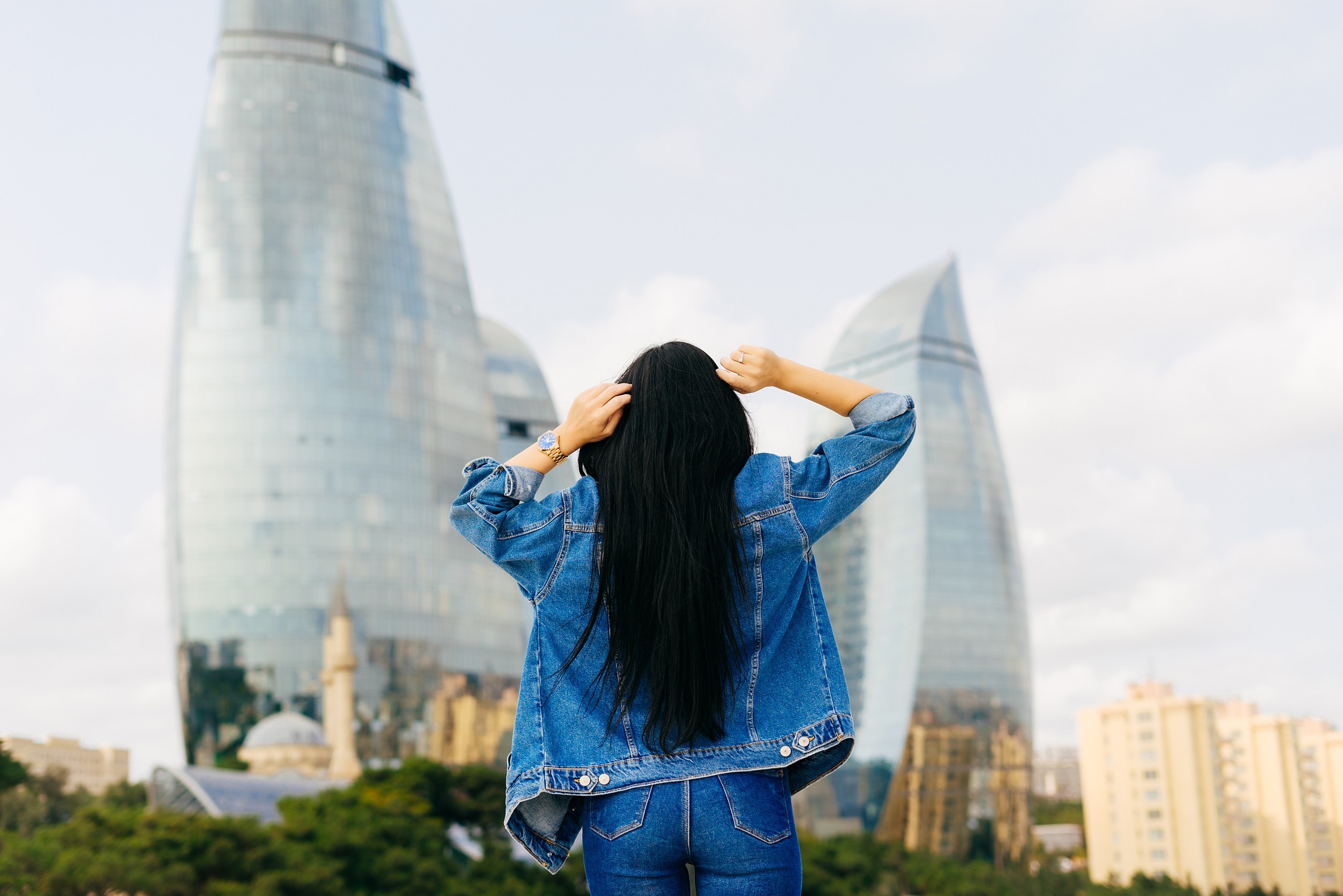 Une jeune fille brune aux cheveux longs voyage en vacances et pose devant des bâtiments modernes. Une jeune fille brune aux cheveux longs voyage en vacances et pose devant des bâtiments modernes.