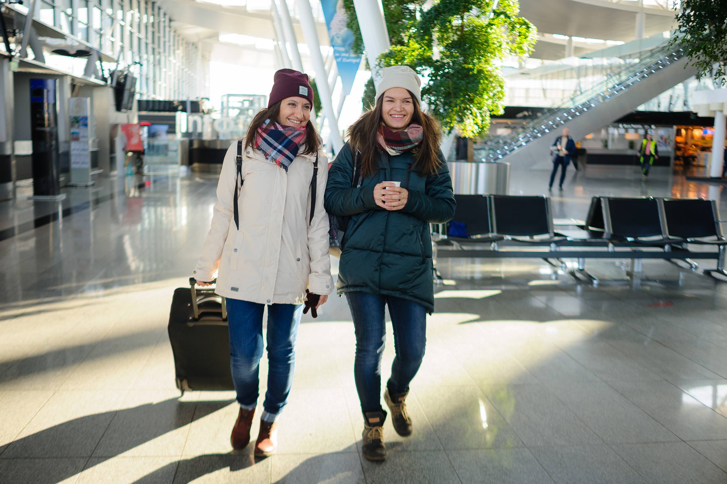 Des passagers dans la salle d'attente de l'aéroport. De jeunes femmes attendent le vol. L'une d'elles tient une valise. Des passagers dans la salle d'attente de l'aéroport. De jeunes femmes attendent le vol. L'une d'elles tient une valise.