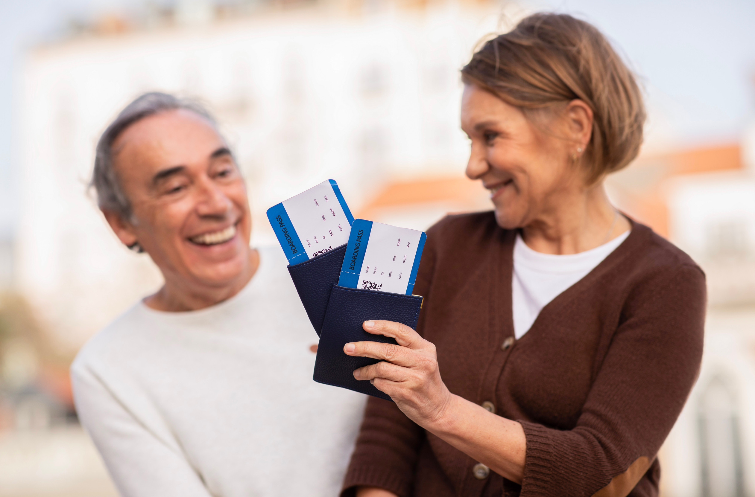 Couple de touristes seniors tenant leurs cartes d'embarquement et passeports à l'extérieur Couple de touristes seniors tenant leurs cartes d'embarquement et passeports à l'extérieur
